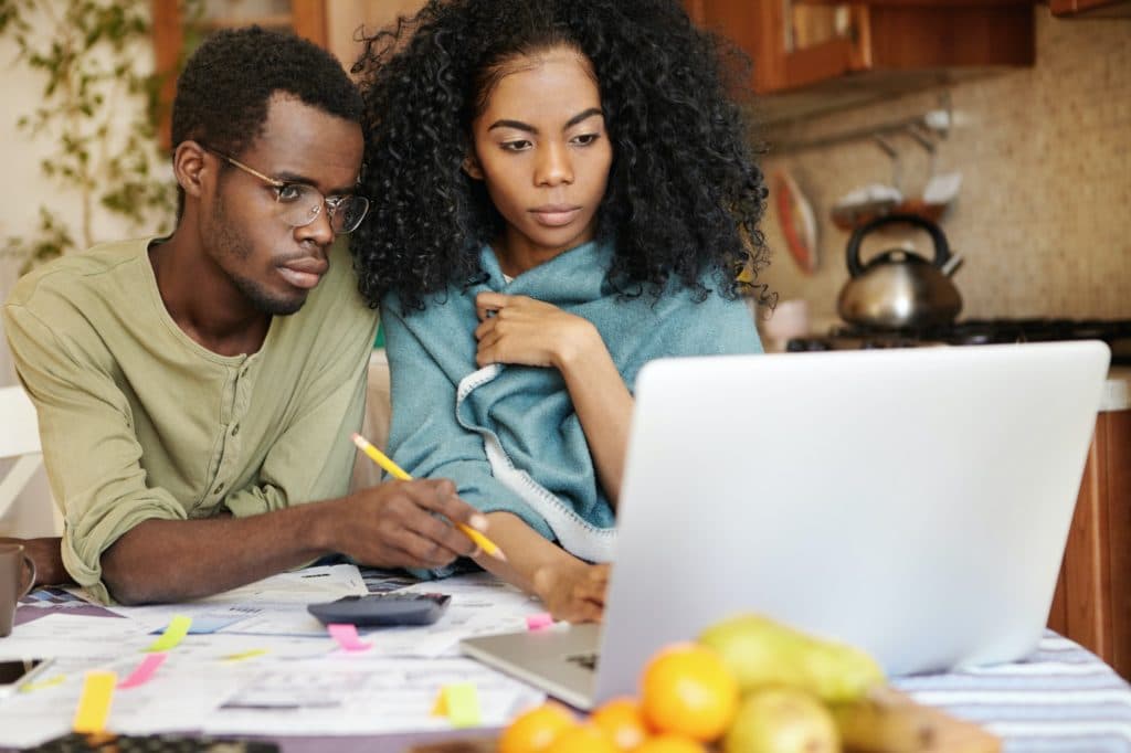 African couple facing financial stress. Young woman with curly hair planning family budget in kitche